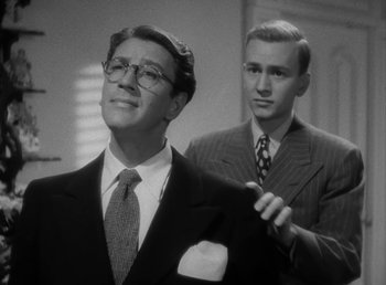 Movie still from “No Time for Love” (1943), directed by Mitchell Leisen – A man in a suit and tie standing next to another man in a suit and tie; Close Up shot, Low angle