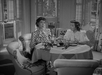 Movie still from “No Time for Love” (1943), directed by Mitchell Leisen – Two women sitting at a table in front of each other; Medium shot, High angle