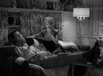 Movie still from “No Time for Love” (1943), directed by Mitchell Leisen – A man and a woman sitting on a couch in a living room; Medium shot, High angle