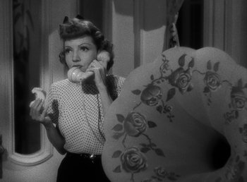 Movie still from “No Time for Love” (1943), directed by Mitchell Leisen – A black and white photo of a woman talking on a phone; Medium shot, High angle