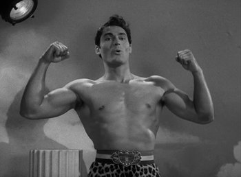 Movie still from “No Time for Love” (1943), directed by Mitchell Leisen – A black - and - white photo of a man flexing his muscles; Medium shot, Low angle