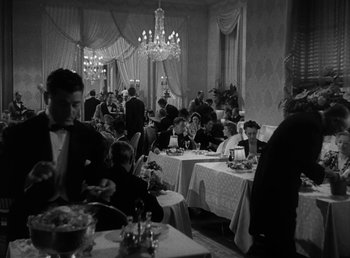 Movie still from “No Time for Love” (1943), directed by Mitchell Leisen – A black and white photo of people sitting at tables in a restaurant; Wide shot, High angle