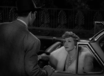 Movie still from “No Time for Love” (1943), directed by Mitchell Leisen – An old photo of a man and a woman sitting in a car; Medium shot, High angle