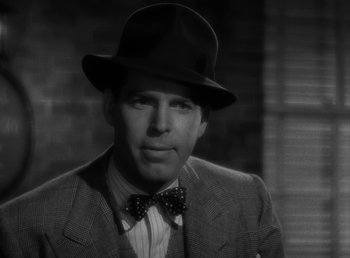 Movie still from “No Time for Love” (1943), directed by Mitchell Leisen – A black and white photo of a man wearing a suit and a hat; Close Up shot, Over the shoulder angle