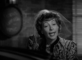 Movie still from “No Time for Love” (1943), directed by Mitchell Leisen – An older woman wearing a veil sitting at a table; Close Up shot, Over the shoulder angle
