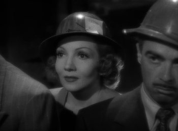 Movie still from “No Time for Love” (1943), directed by Mitchell Leisen – An old photo of a man and a woman wearing a hard hat; Close Up shot, Low angle