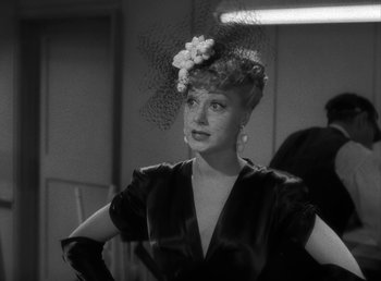 Movie still from “No Time for Love” (1943), directed by Mitchell Leisen – A black and white photo of a woman with a flower in her hair; Close Up shot, Over the shoulder angle