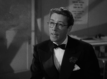 Movie still from “No Time for Love” (1943), directed by Mitchell Leisen – A man in a suit and tie wearing glasses and a bow tie; Close Up shot, High angle