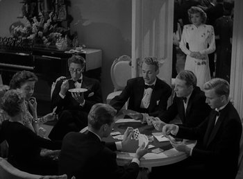 Movie still from “No Time for Love” (1943), directed by Mitchell Leisen – A black and white photo of a group of men sitting at a table; Medium shot, High angle