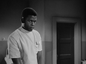Movie still from “No Way Out” (1950), directed by Joseph L. Mankiewicz – A black and white photo of a man standing in front of a door; Medium shot, Low angle