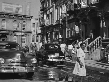 Movie still from “No Way Out” (1950), directed by Joseph L. Mankiewicz – An old black and white photo of a woman walking down the street; Wide shot, Low angle