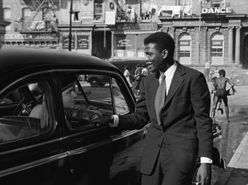 Movie still from “No Way Out” (1950), directed by Joseph L. Mankiewicz – A black and white photo of a man in a suit in a car; Medium shot, Low angle