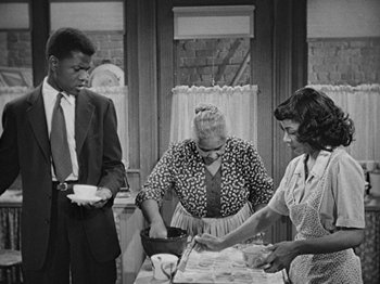 Movie still from “No Way Out” (1950), directed by Joseph L. Mankiewicz – A group of people standing around a table with food on top of it; Medium shot, High angle