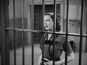 Movie still from “No Way Out” (1950), directed by Joseph L. Mankiewicz – A black and white photo of a woman behind bars; Medium shot, Low angle