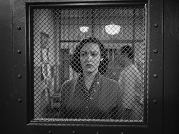Movie still from “No Way Out” (1950), directed by Joseph L. Mankiewicz – A black - and - white photo of a woman behind a fence; Medium shot, Low angle