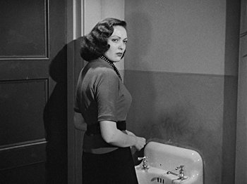 Movie still from “No Way Out” (1950), directed by Joseph L. Mankiewicz – A black and white photo of a woman standing in front of a bathroom sink; Medium shot, Over the shoulder angle