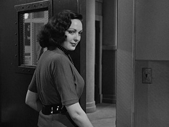 Movie still from “No Way Out” (1950), directed by Joseph L. Mankiewicz – A black - and - white photo of a woman standing in front of a door; Medium shot, Over the shoulder angle