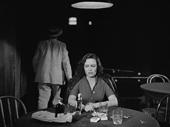 Movie still from “No Way Out” (1950), directed by Joseph L. Mankiewicz – A woman sitting at a table with a glass of wine; Medium shot, High angle