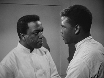 A black and white photo of two men looking at each other