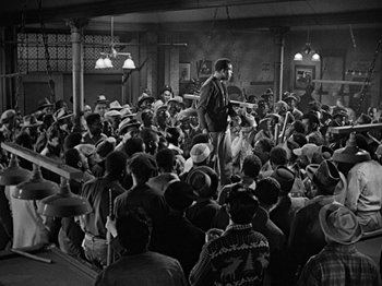 Movie still from “No Way Out” (1950), directed by Joseph L. Mankiewicz – A large group of people sitting in a room; Wide shot, High angle