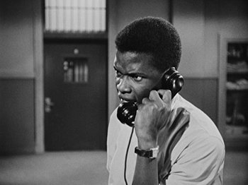 Movie still from “No Way Out” (1950), directed by Joseph L. Mankiewicz – A black and white photo of a man talking on a phone; Close Up shot, High angle