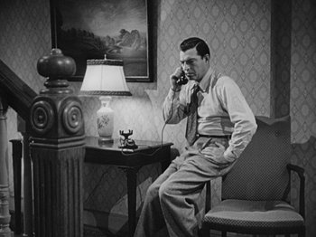Movie still from “No Way Out” (1950), directed by Joseph L. Mankiewicz – A black and white photo of a man talking on a phone; Medium shot, High angle