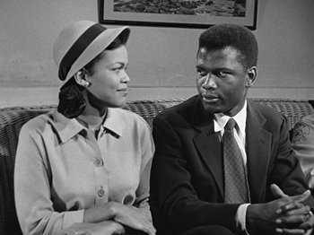 Movie still from “No Way Out” (1950), directed by Joseph L. Mankiewicz – An old photo of a man and a woman sitting on a couch; Medium shot, Low angle