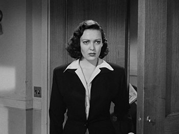 Movie still from “No Way Out” (1950), directed by Joseph L. Mankiewicz – A black - and - white photo of a woman in a suit; Medium shot, Over the shoulder angle