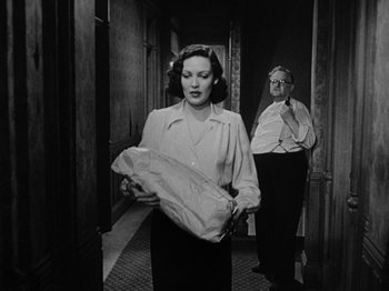 Movie still from “No Way Out” (1950), directed by Joseph L. Mankiewicz – A woman holding a paper bag while standing next to a man in a hallway; Medium shot, Low angle