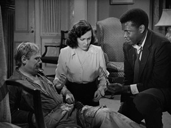 Movie still from “No Way Out” (1950), directed by Joseph L. Mankiewicz – Two men and a woman sitting in a living room; Medium shot, High angle