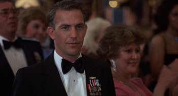 Movie still from “No Way Out” (1987), directed by Roger Donaldson – A man in a tuxedo with medals around his neck; Close Up shot, Over the shoulder angle