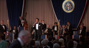 Movie still from “No Way Out” (1987), directed by Roger Donaldson – A group of men in tuxedos are performing in front of an audience; Wide shot, Low angle