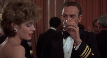 Movie still from “No Way Out” (1987), directed by Roger Donaldson – A man in a tuxedo drinking a glass of wine; Close Up shot, Over the shoulder angle