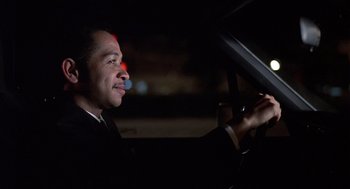 Movie still from “No Way Out” (1987), directed by Roger Donaldson – A man in a suit driving a car at night; Close Up shot, Low angle
