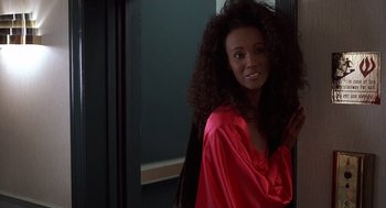 Movie still from “No Way Out” (1987), directed by Roger Donaldson – A woman in a red robe smiling for the camera; Medium shot, Over the shoulder angle