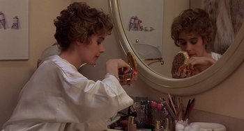 Movie still from “No Way Out” (1987), directed by Roger Donaldson – A woman putting makeup on in front of a mirror; Close Up shot, Low angle