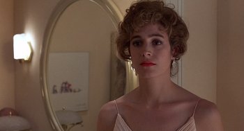 Movie still from “No Way Out” (1987), directed by Roger Donaldson – A woman in a white dress looking at a mirror; Close Up shot, Over the shoulder angle