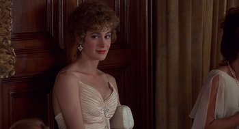 Movie still from “No Way Out” (1987), directed by Roger Donaldson – A woman in a white dress is posing for a picture; Close Up shot, Over the shoulder angle