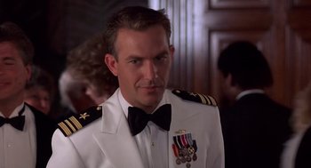 Movie still from “No Way Out” (1987), directed by Roger Donaldson – A person wearing a suit and bow tie; Close Up shot, Low angle