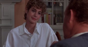 Movie still from “No Way Out” (1987), directed by Roger Donaldson – A woman sitting at a table with a book in front of her; Close Up shot, Over the shoulder angle