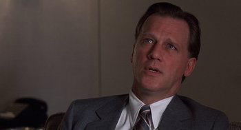 Movie still from “No Way Out” (1987), directed by Roger Donaldson – A person wearing a suit and tie; Close Up shot, Low angle