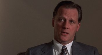 Movie still from “No Way Out” (1987), directed by Roger Donaldson – A person wearing a suit and tie; Close Up shot, Low angle