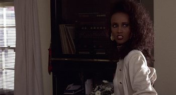 Movie still from “No Way Out” (1987), directed by Roger Donaldson – A woman standing in front of an entertainment center; Close Up shot, Over the shoulder angle