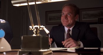 Movie still from “No Way Out” (1987), directed by Roger Donaldson – A man sitting at a table with a pen and a laptop; Close Up shot, Low angle