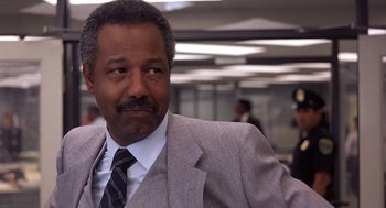 Movie still from “No Way Out” (1987), directed by Roger Donaldson – A man in a suit and tie in an office setting; Close Up shot, Low angle