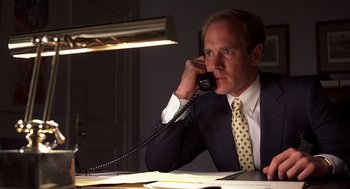 Movie still from “No Way Out” (1987), directed by Roger Donaldson – A man sitting at a desk talking on a phone; Close Up shot, Low angle