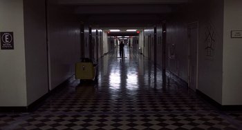Movie still from “No Way Out” (1987), directed by Roger Donaldson – A person walking down a hallway with a suitcase; Extreme Wide shot, High angle