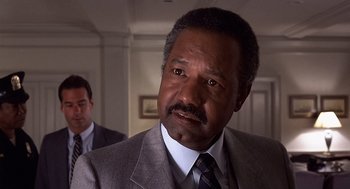 Movie still from “No Way Out” (1987), directed by Roger Donaldson – A man in a suit and tie looking at the camera; Close Up shot, Low angle