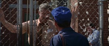 Movie still from “Norma Rae” (1979), directed by Martin Ritt – Two men talking to each other in front of a chain link fence; Medium shot, Over the shoulder angle