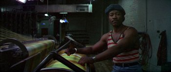 Movie still from “Norma Rae” (1979), directed by Martin Ritt – A man standing in front of an ironing board in a room; Medium shot, Low angle